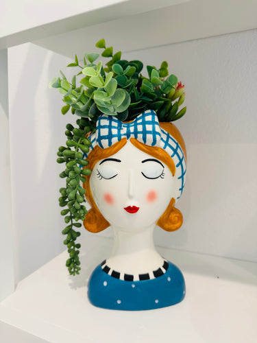 Decorative vase shaped like a woman's head with plants on a white background